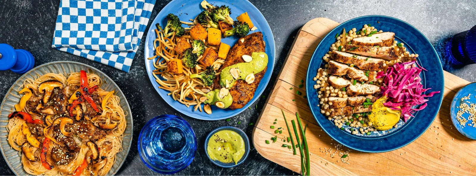 Three chef-made meals: noodles with mushrooms and peppers, crusted chicken with pasta, and sliced chicken over couscous