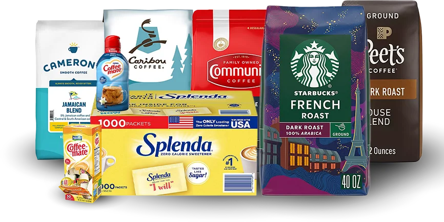 Assorted coffee supplies including Starbucks French Roast, Peet's coffee, Caribou Coffee, Community Coffee, Splenda sweeteners and Coffee-Mate creamer on a gray background representing Vendgo's office pantry program in Atlanta.