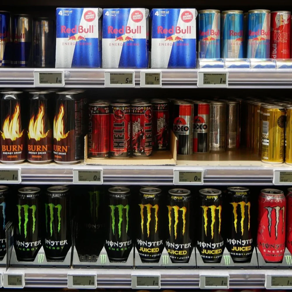 Rows of energy drink cans, including Red Bull, Monster, and Burn, neatly organized on Vendgo smart cooler shelves in an Atlanta logistics warehouse.
