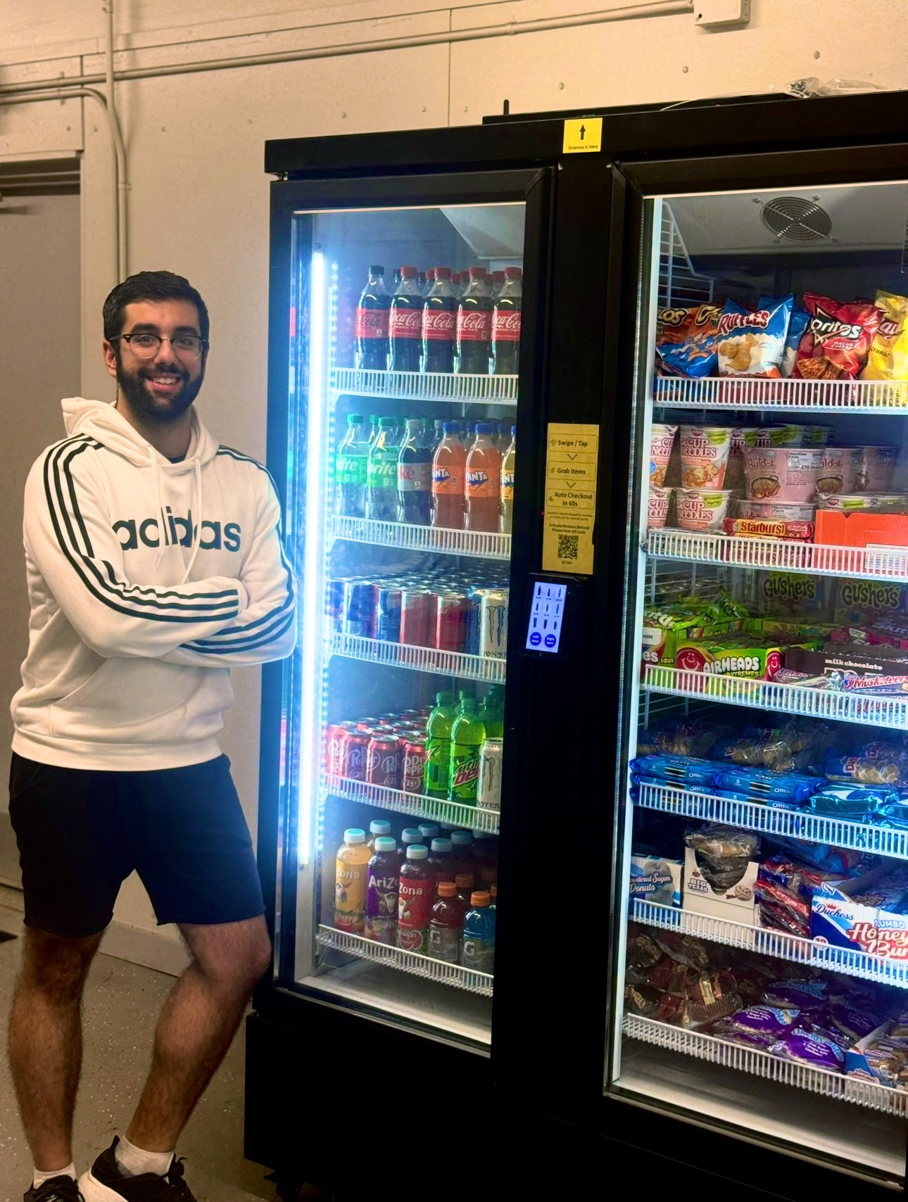 VendGO owner standing next to a modern, fully stocked combo vending machine in Atlanta featuring snacks and cold drinks.